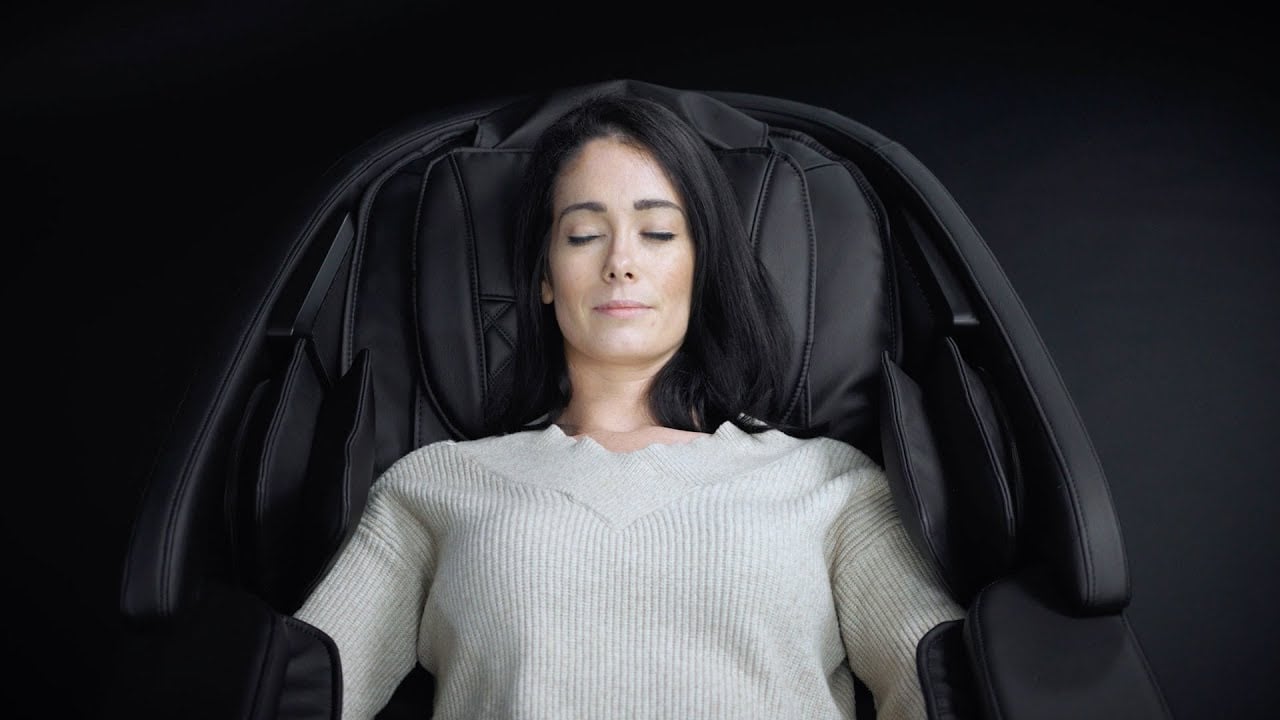 Woman laying in a massage chair, with her eyes closed.