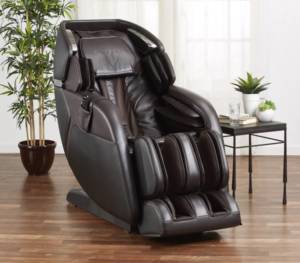 Black leather-upholstered massage chair in a room with white walls, hardwood floors and assorted plants.
