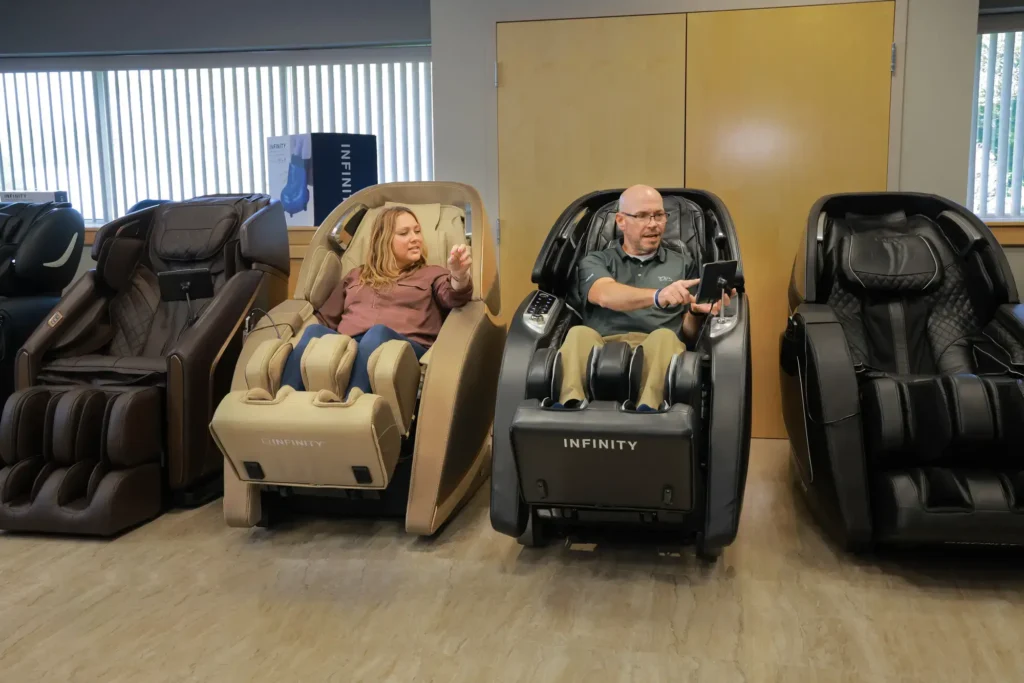two members of the MCS review team sitting in and testing different massage chairs within the Massage Chair Store show room.
