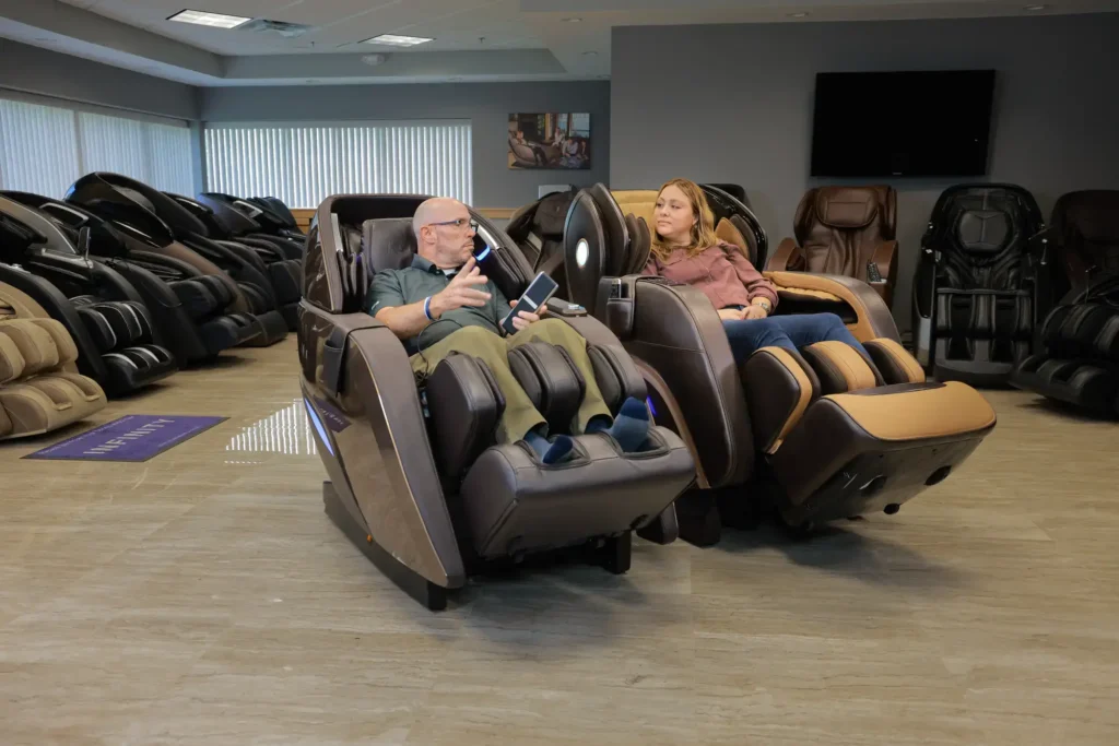 two members of the MCS review team sitting in and testing different massage chairs within the Massage Chair Store show room.