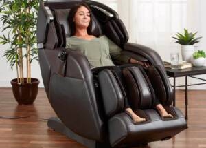 A woman is reclining in a brown massage chair in her meditation corner, surrounded by several plants.