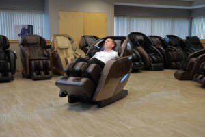 A member of the Massage Chair Store Review Team reclines in a brown Kyota M989 Yutaka massage chair within the MCS test facility.