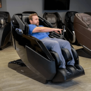 A-member-of-the-Massage-Chair-Review-Team-sits-in-and-uses-the-control-panel-of-a-black-Infinity-Imperial-Syner-D-massage-chair.