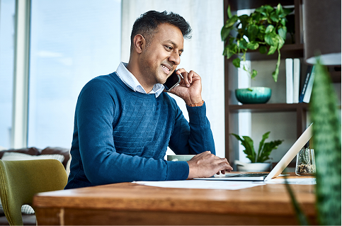 man sitting at a desk while talking on his phone